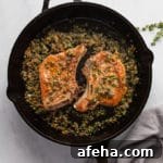 Pork chops in a cast iron skillet topped with pan sauce.
