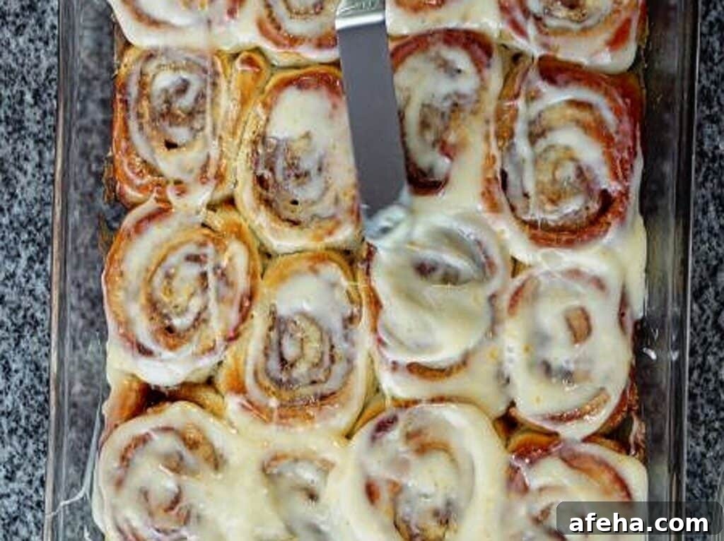 using offset spatula to spread remaining orange icing on top of rolls.