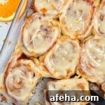 baking pan full of gluten free orange rolls with slice of orange alongside.