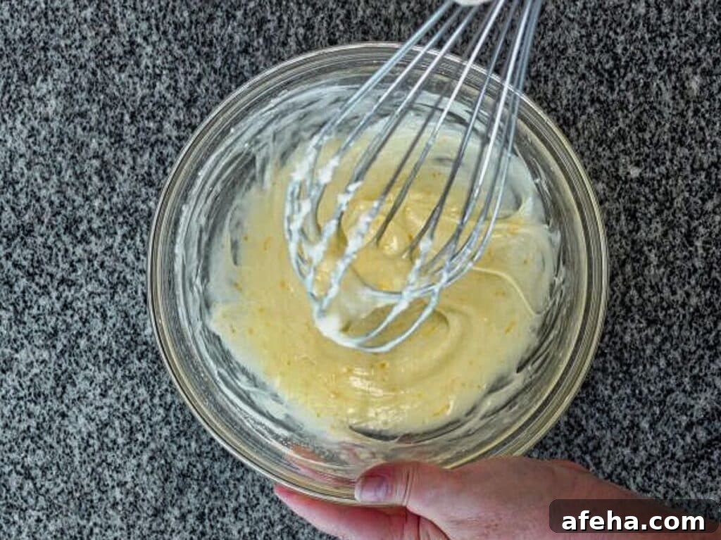 whisking orange icing in small glass bowl.