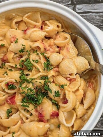 A dish of cheesy barbeque pasta sprinkled with chopped parsley.