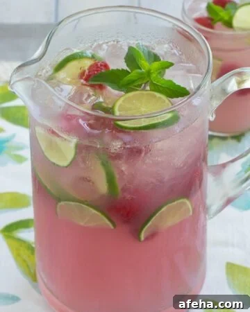 A glass pitcher full of pink lemonade.