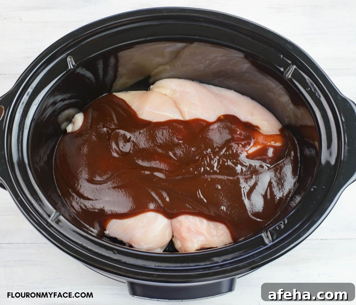 Chicken with barbecue sauce inside a slow cooker.