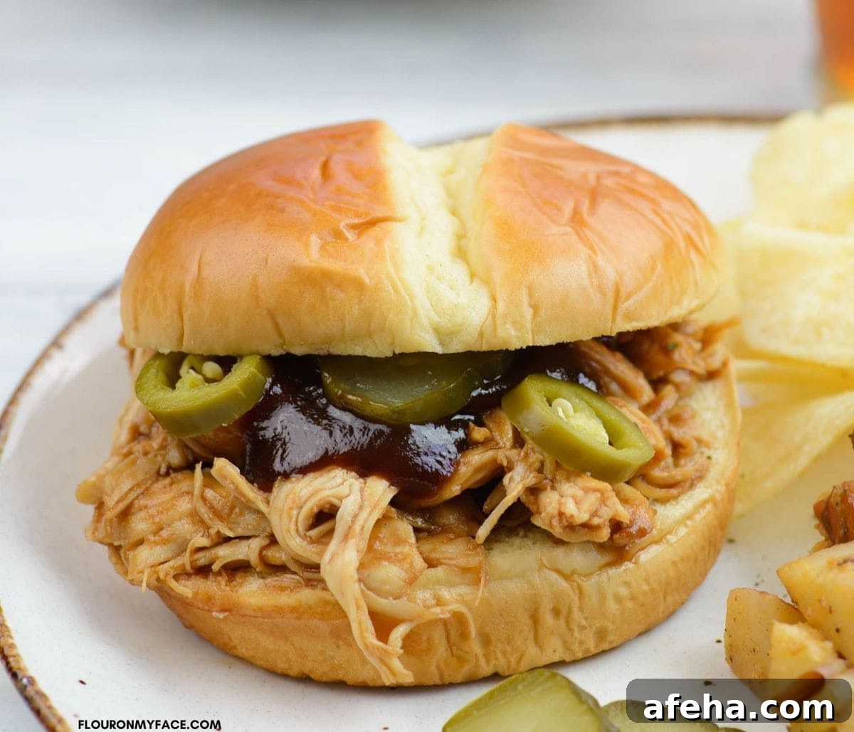 Close up photo of a barbecued chicken sandwich on a plate.