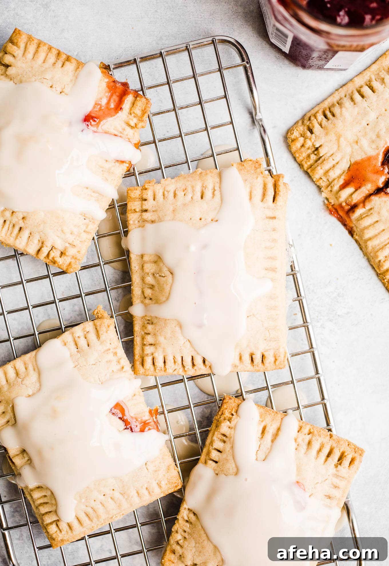 Glazed toaster pastries with jam on a cooling rack.