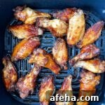 overhead shot of cooked marinated chicken wings in the air fryer basket