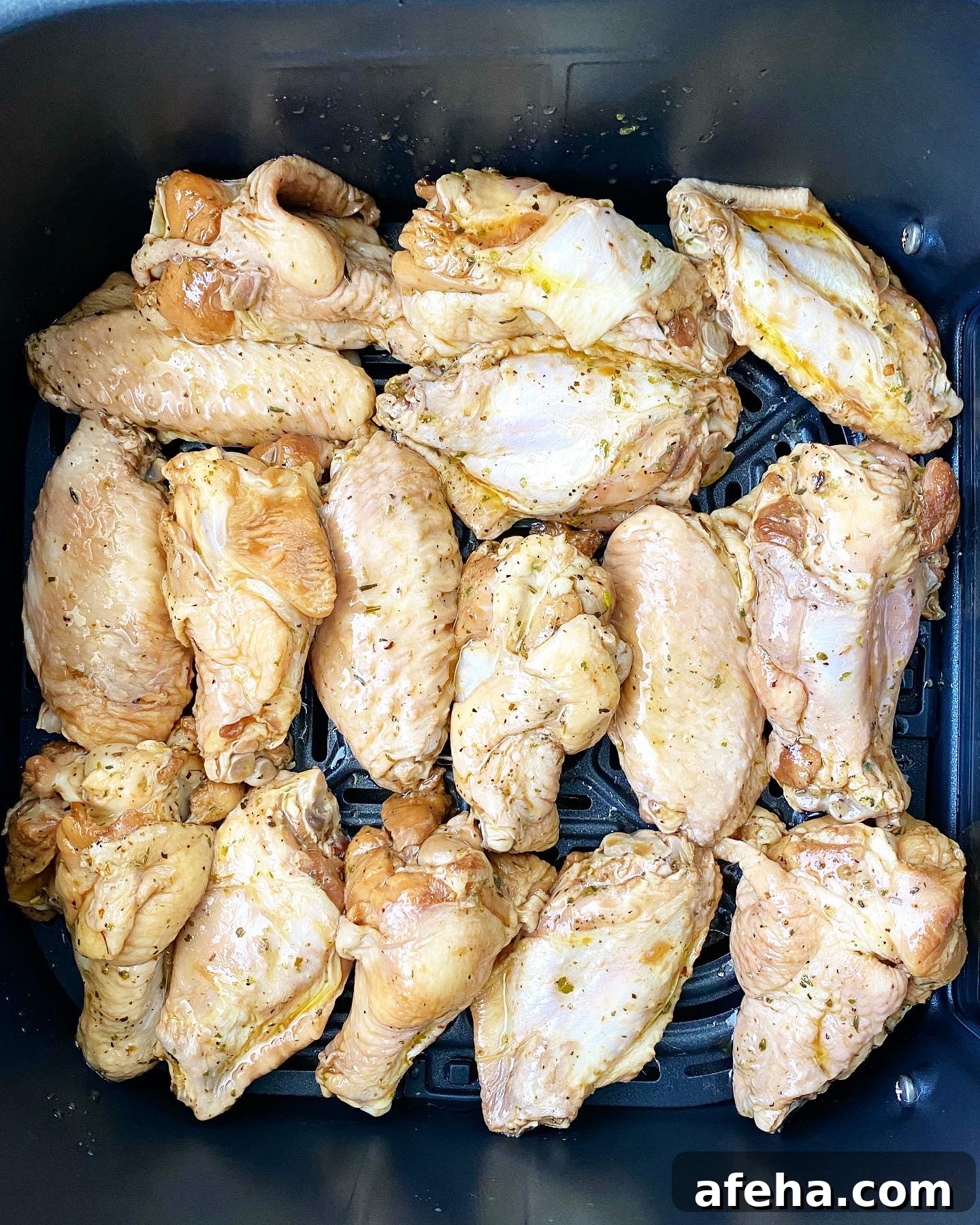 overhead shot of raw, uncooked marinated chicken wings in the air fryer basket