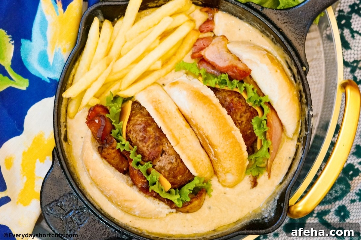 Cheeseburger sliced in half cut side face down in a cast iron skillet full of queso next to fries