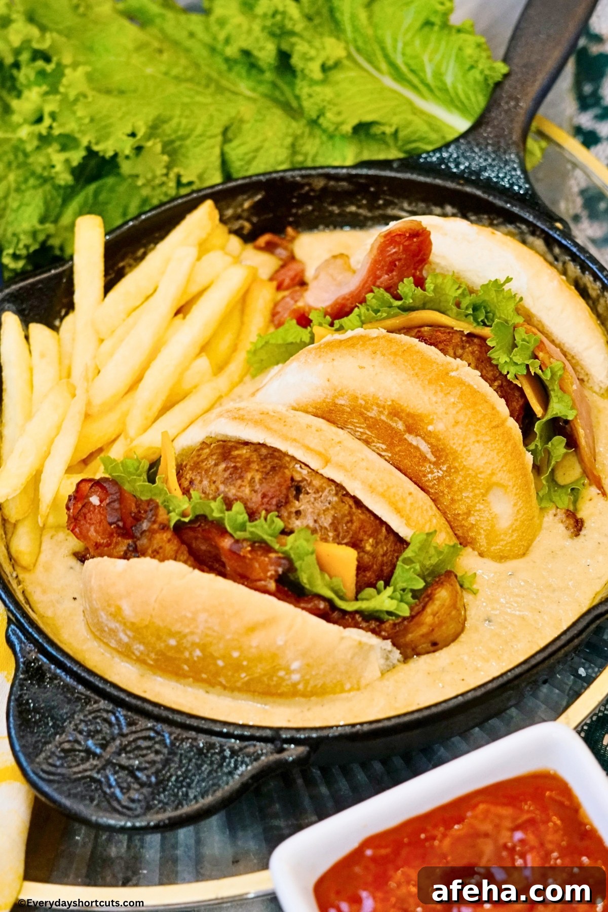 A pool of queso in a cast iron skillet with fries and a cheeseburger with bacon cut in half