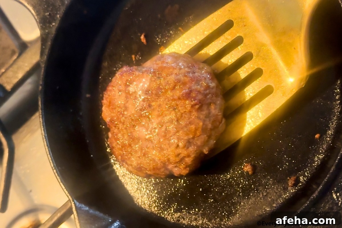 burger patty cooking in a cast iron skillet