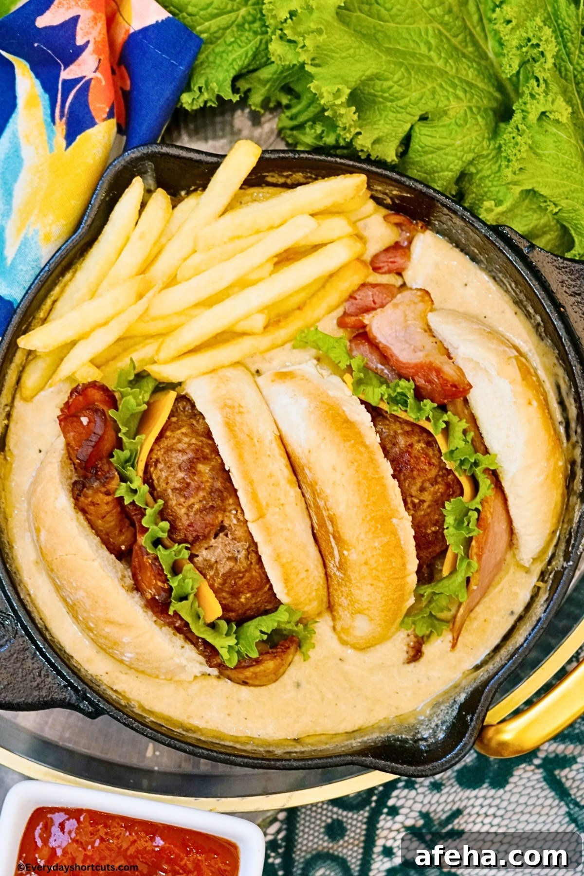 Fries and cheeseburger in a skillet full of queso