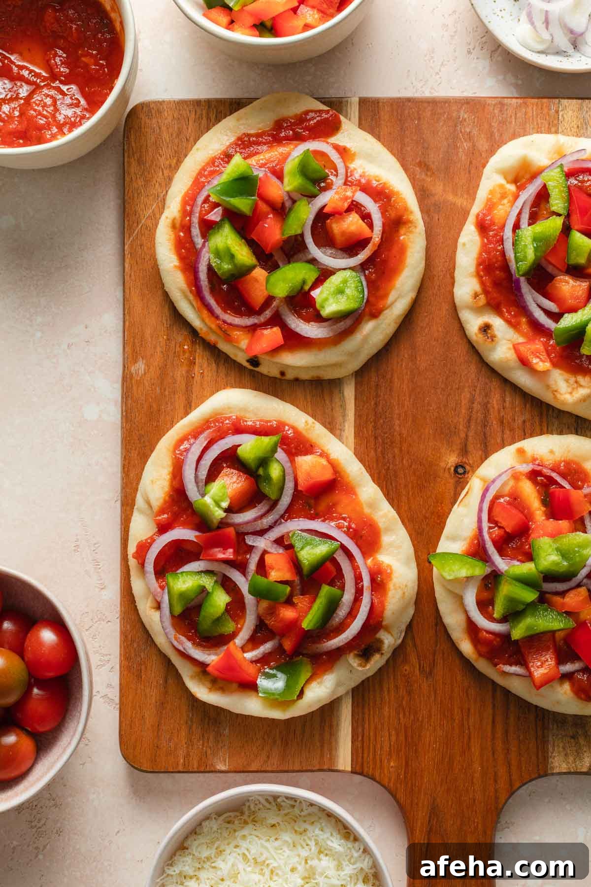 Mini Naan Bread Pizzas Made in the Air Fryer 5 Naan bread mini pizzas with veggies arranged on top.