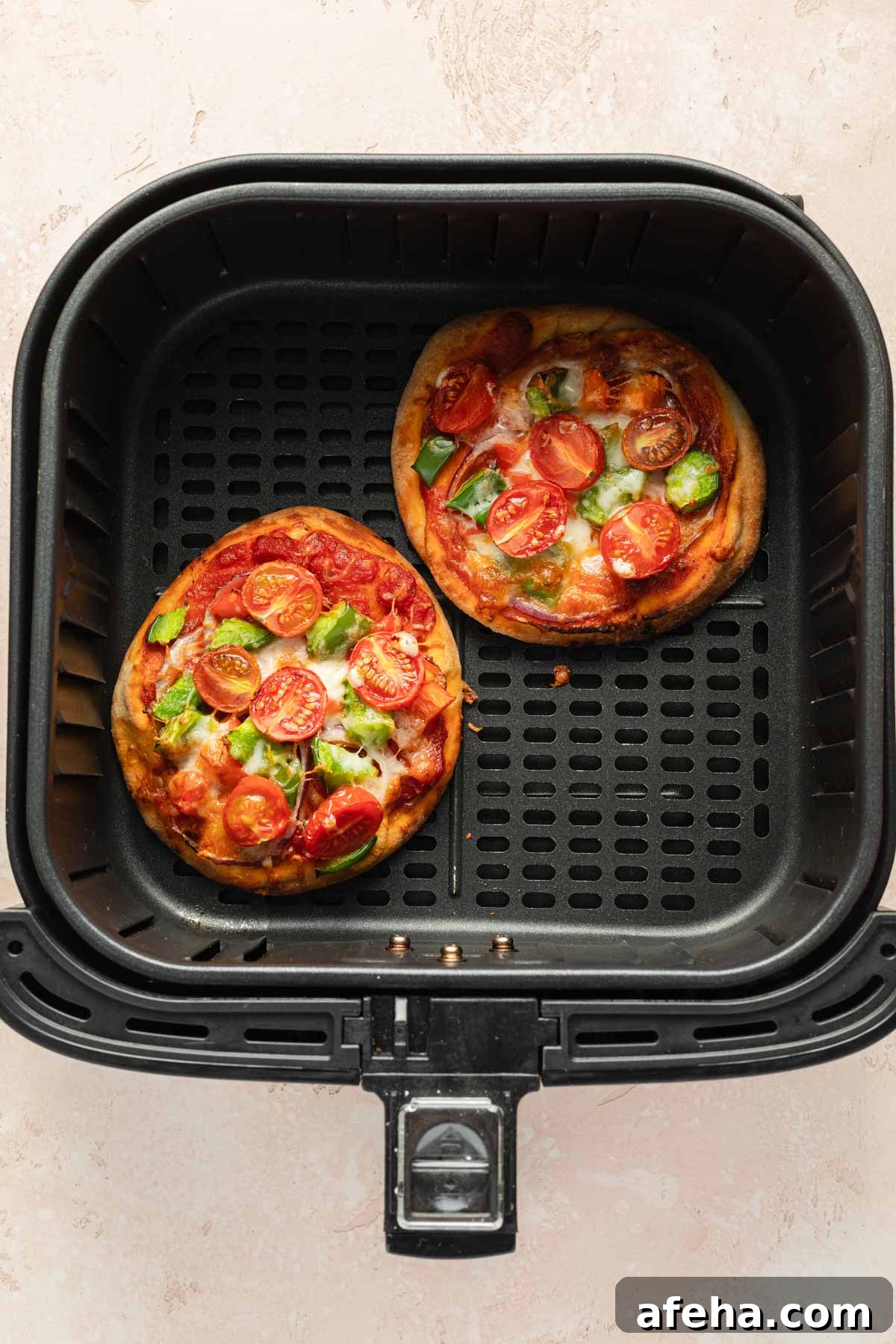 Mini Naan Bread Pizzas Made in the Air Fryer 6 Two mini pizzas in an air fryer basket.