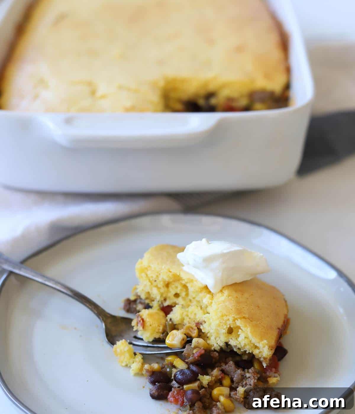 Casserole served on plate topped with sour cream. 