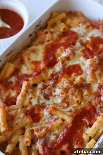 Meatless baked ziti in casserole dish with sauce on side.
