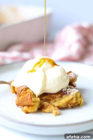 slice of brioche french toast casserole with whipped cream and maple syrup pouring over it