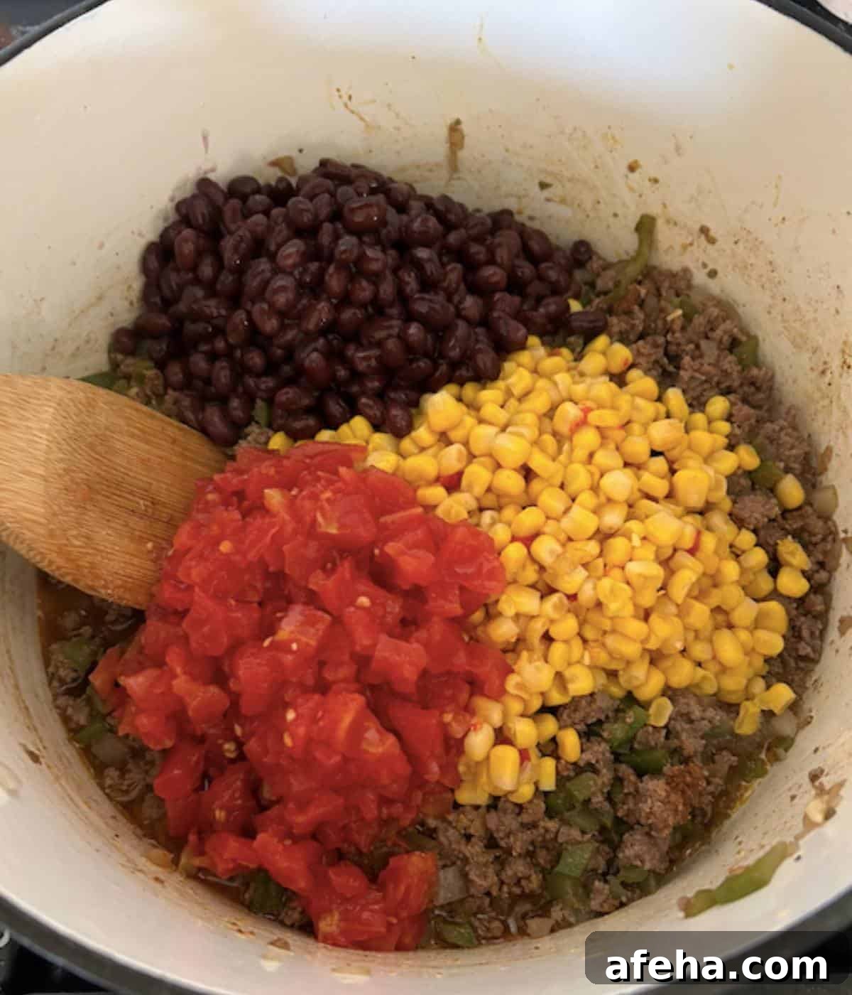 Corn, beans, and rotel on top of ground beef.