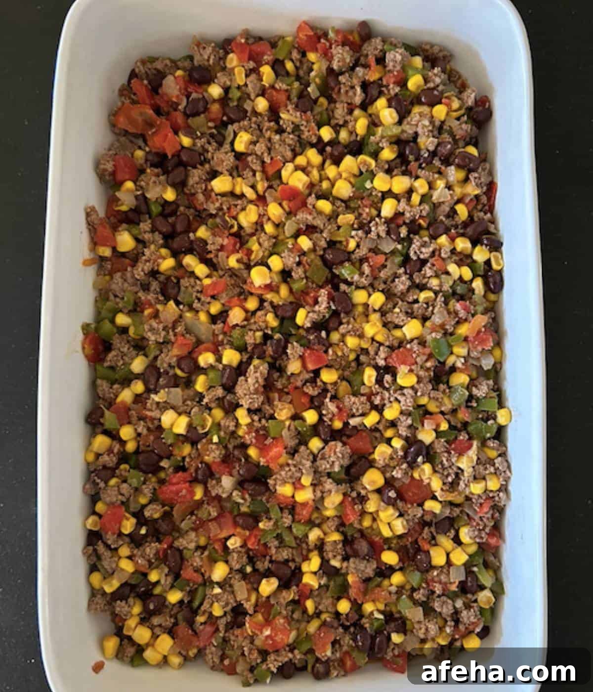 Ground beef base layer in casserole dish.