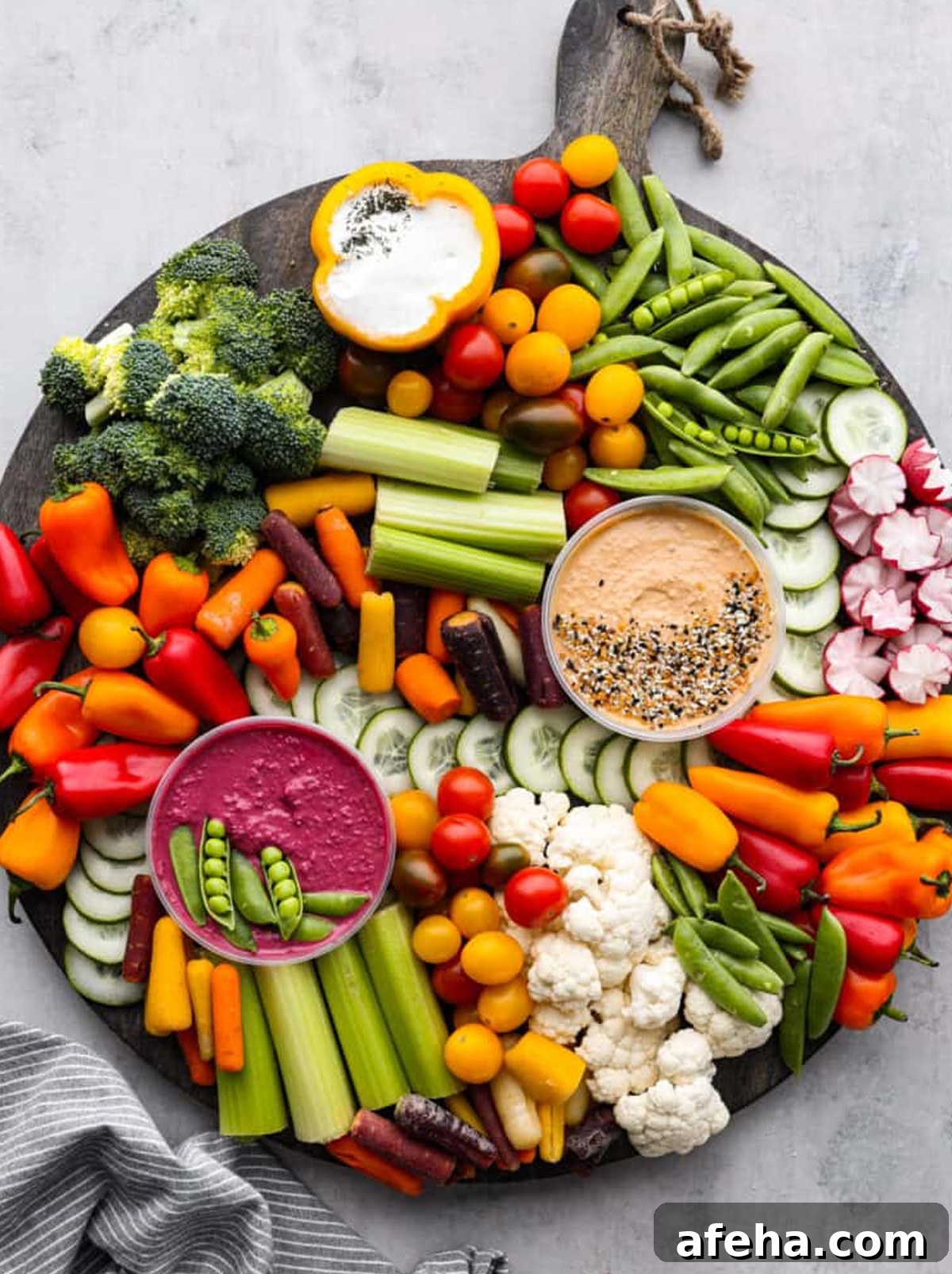 Recipe Critic displays an celery, peppers, broccoli, tomatoes, and dips on their veggie charcuterie board.