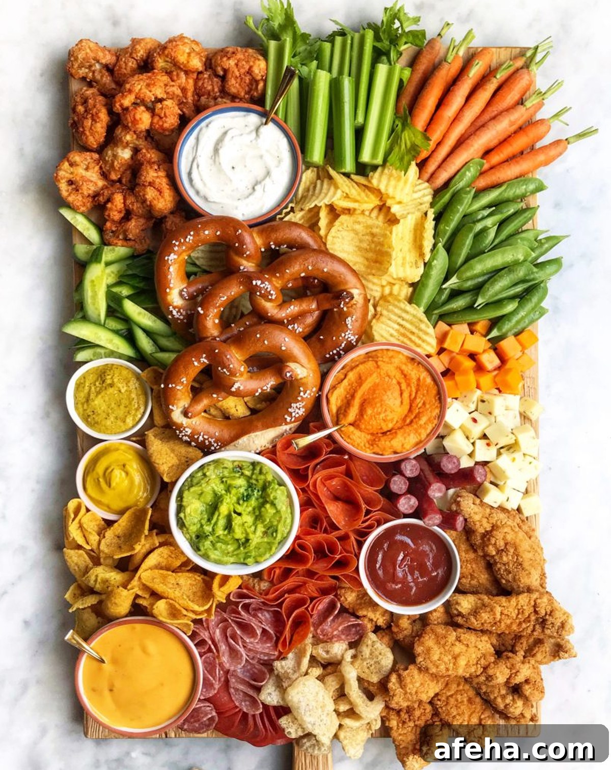 The Delicious Life's board is full of chips, veggies, meats, cheese, pretzels. and dips.