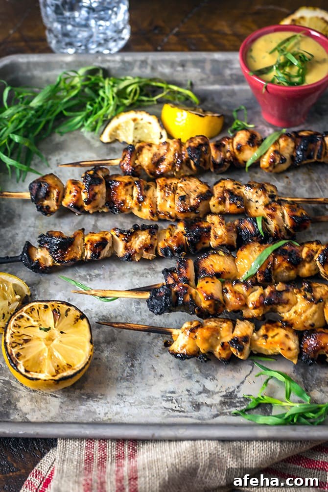 A side view of Tarragon Mustard Chicken Skewers set on a silver baking sheet.