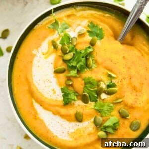 A bowl of pumpkin and sweet potato soup topped with chopped cilantro and pumpkin seeds.