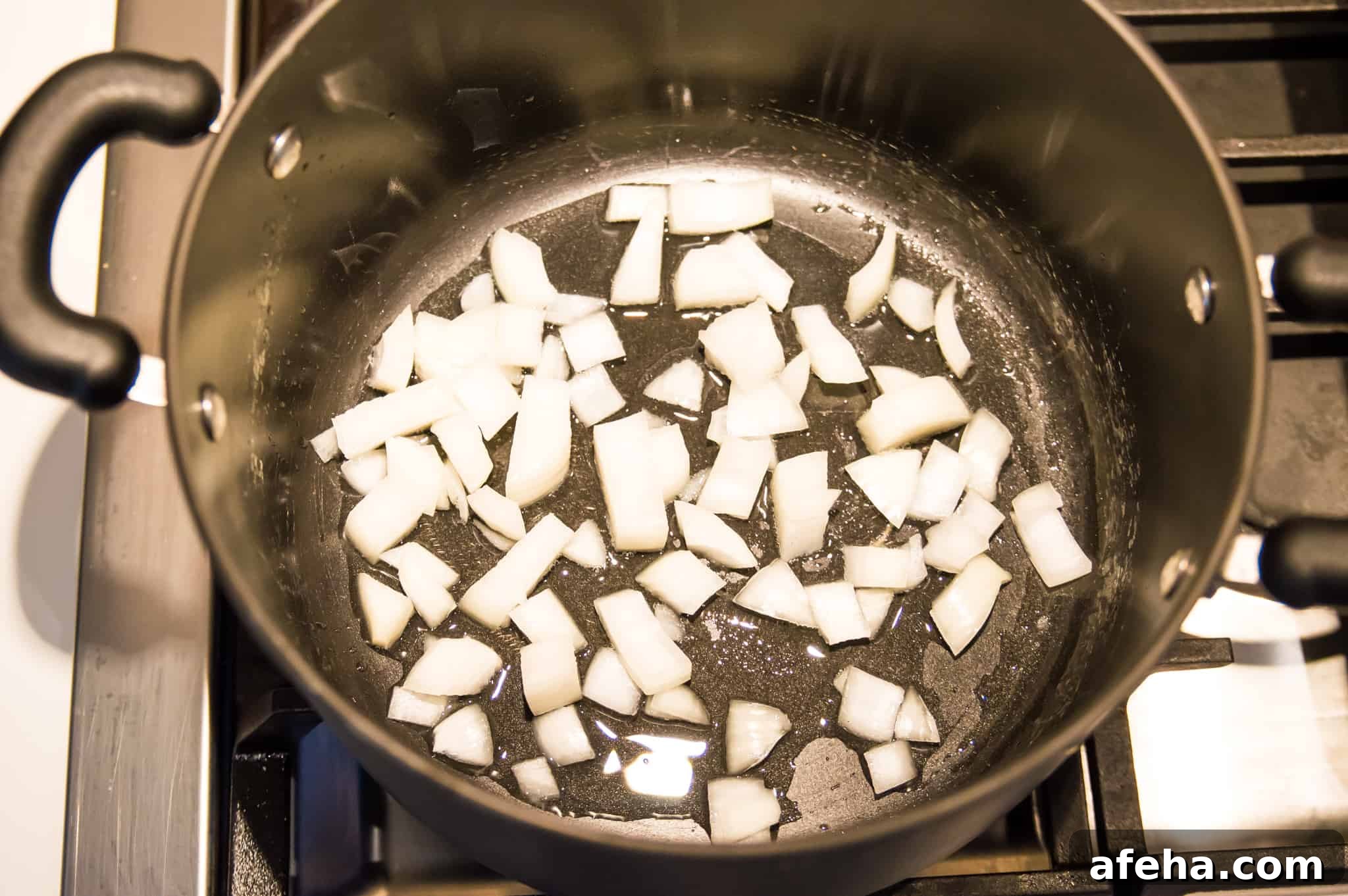 Chopped onion cooking in a pot on the stovetop.