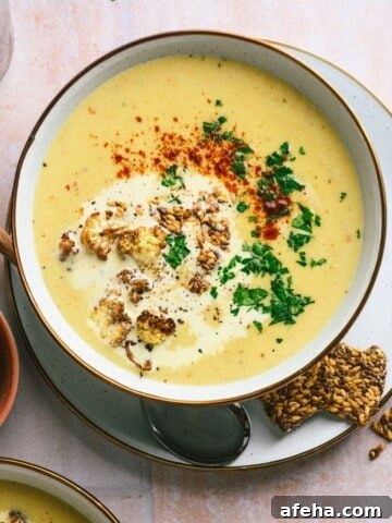 A bowl of creamy soup topped with fresh parsley and crushed crackers.