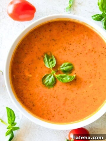 A bowl of cherry tomato soup topped with fresh basil.