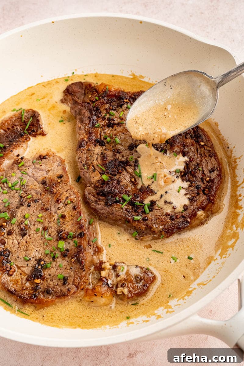 a spoon drips cognac sauce over the steak nestled in the pan.