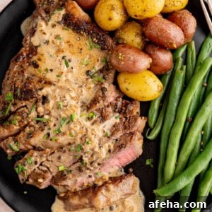 Steak au poivre on a black plate with potatoes and green beans.