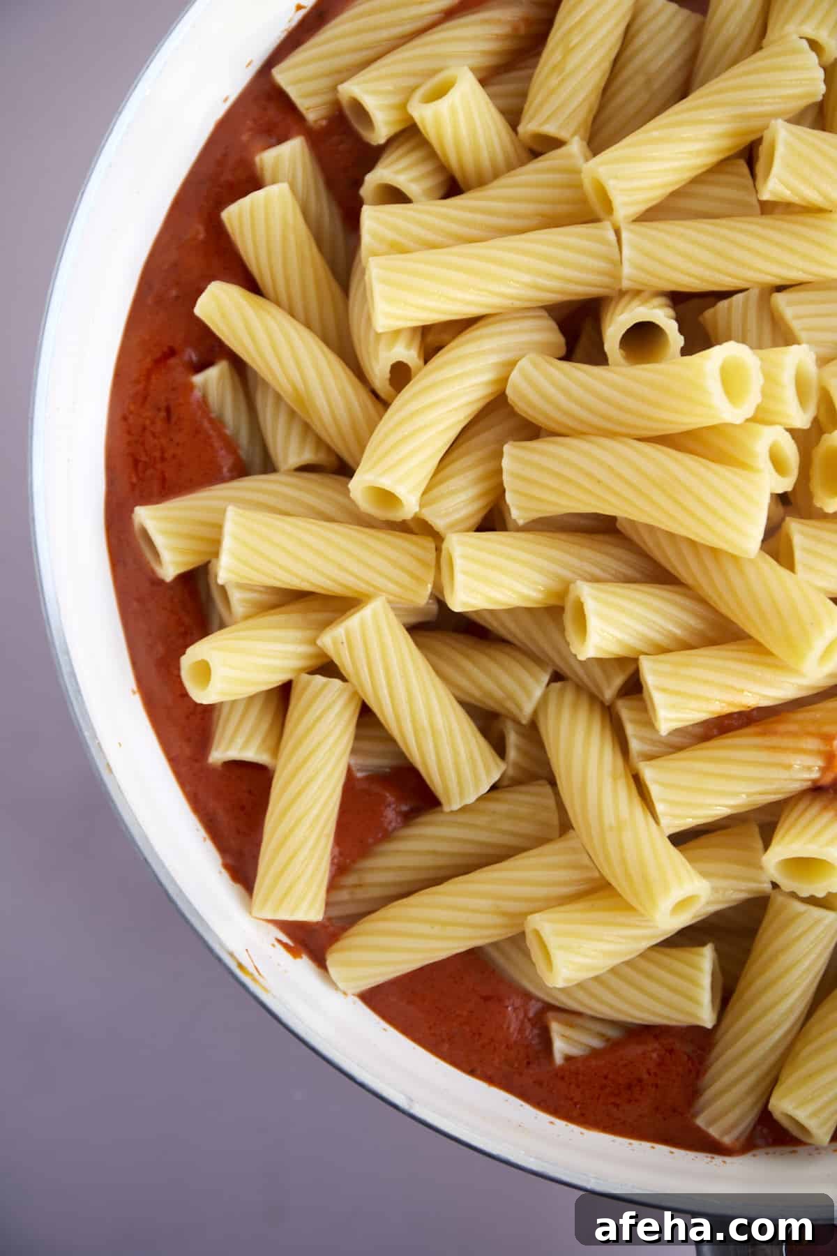 rigatoni noodles on top of red sauce.