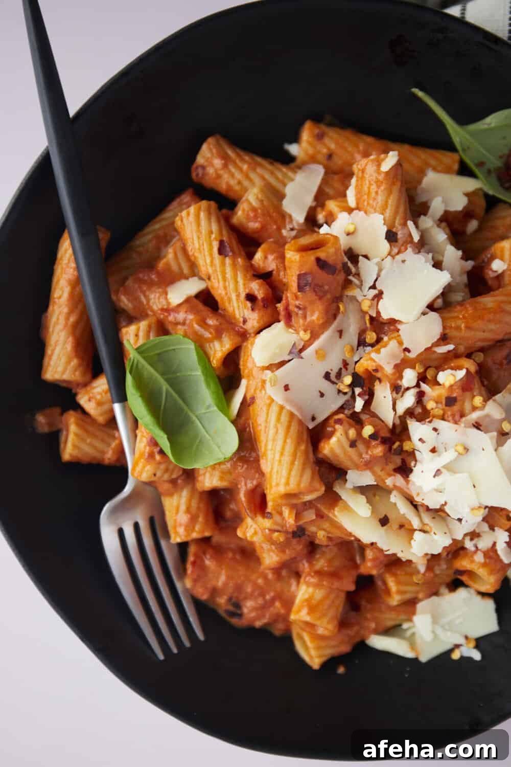 close up image of a bowl of rigatoni pasta with a fork on the side.