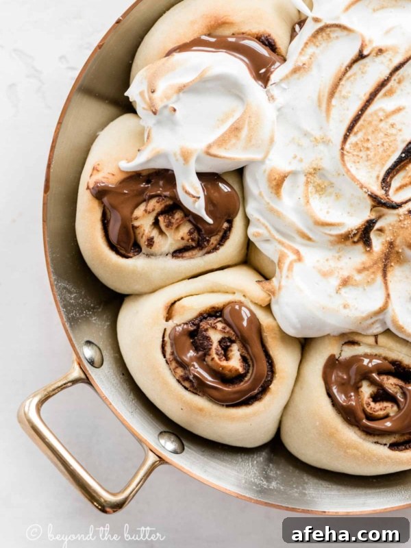 Overhead closeup image of s'mores rolls partially covered with marshmallow topping.