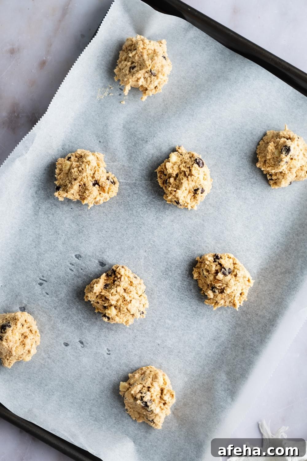 An overhead view of cookie dough balls on parchment lined baking tray.