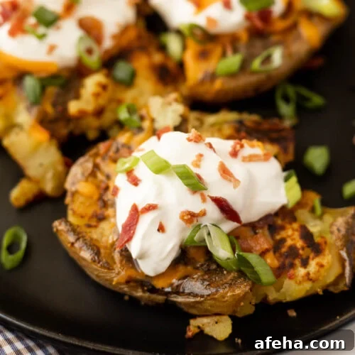 Two baked potatoes topped with sour cream and bacon.