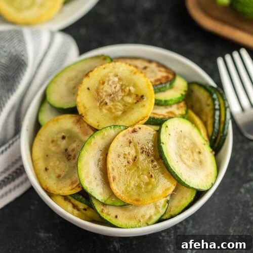 A white bowl filled with sautéed slices of zucchini and squash.