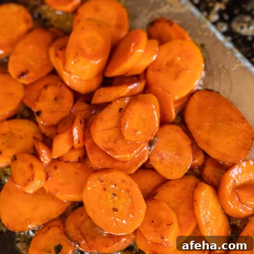 Cooked sliced carrots cooking in a glaze on the griddle