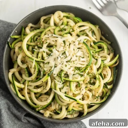 A bowl of zucchini noodles topped with shredded cheese.