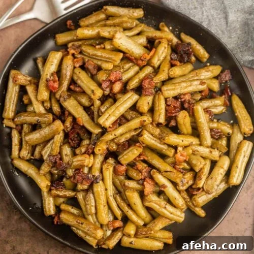 A plate of green beans with bacon and a fork.