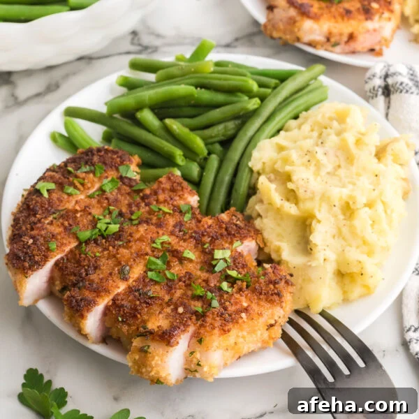 Parmesan breaded pork chops on a plate with mashed potatoes and green beans