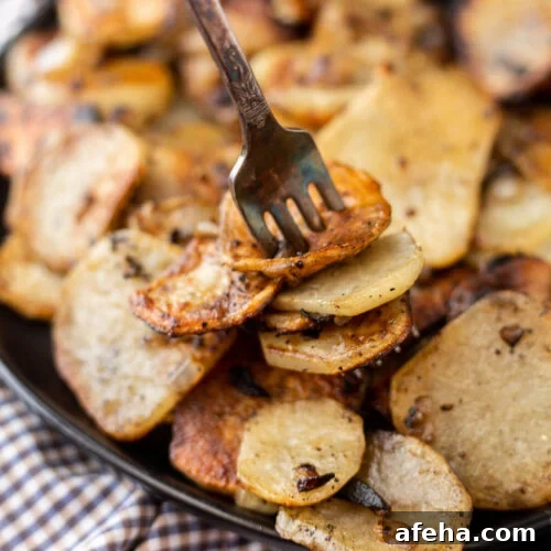 A fork is lifting potatoes from a pan.