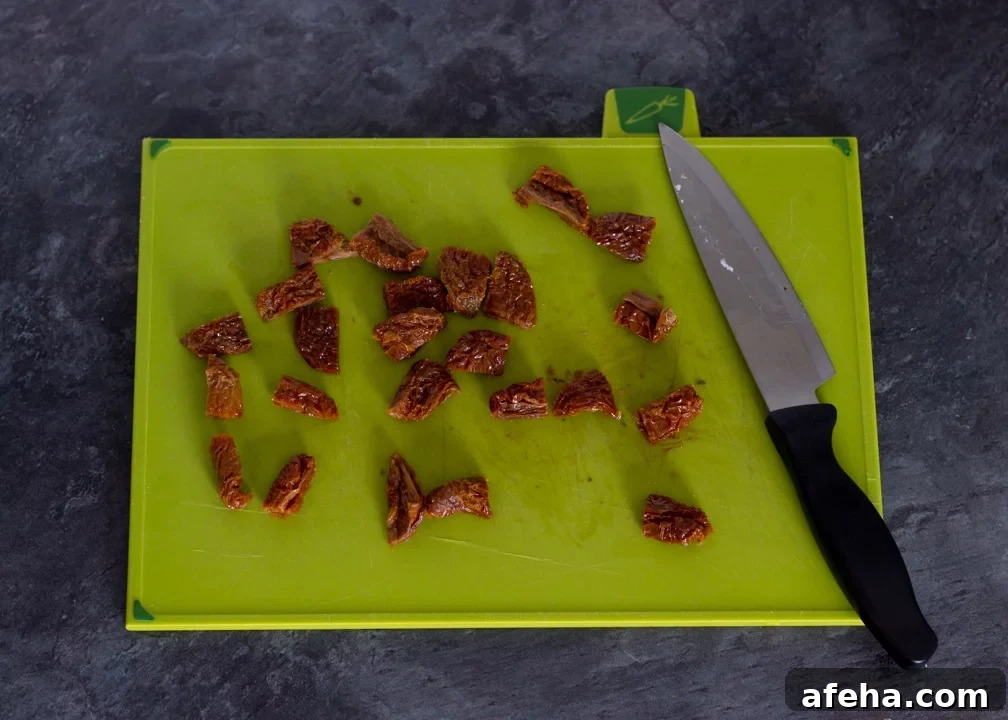 Chopped sun dried tomatoes on a chopping board.