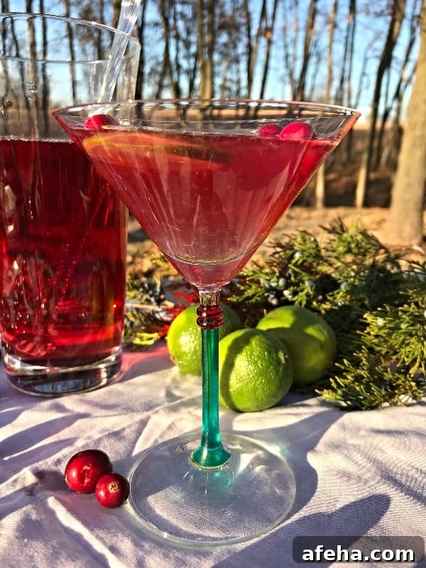 The Classic Cosmopolitan shown from the side with a pitcher of the cocktail
