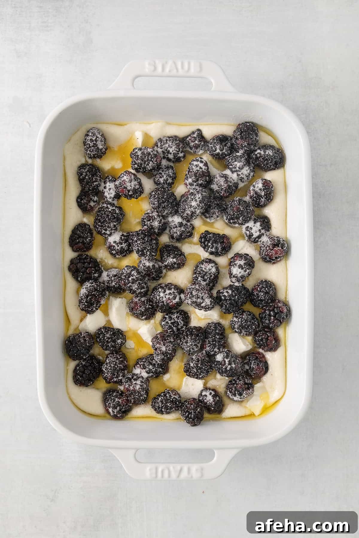 Blackberry Cobbler with Cream Cheese Swirl: Rustic Summer Dessert 5 a white dish filled with berries and cream.
