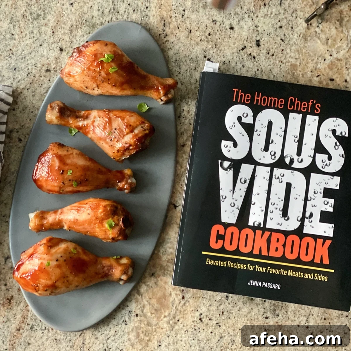 Cooked chicken legs on gray oval plate next to cookbook