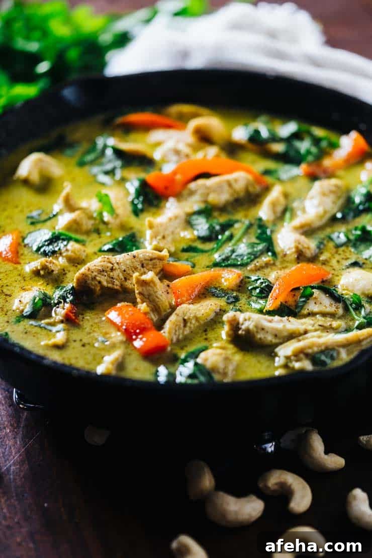 Chicken curry made with coconut milk with spinach and peppers in a cast iron skillet