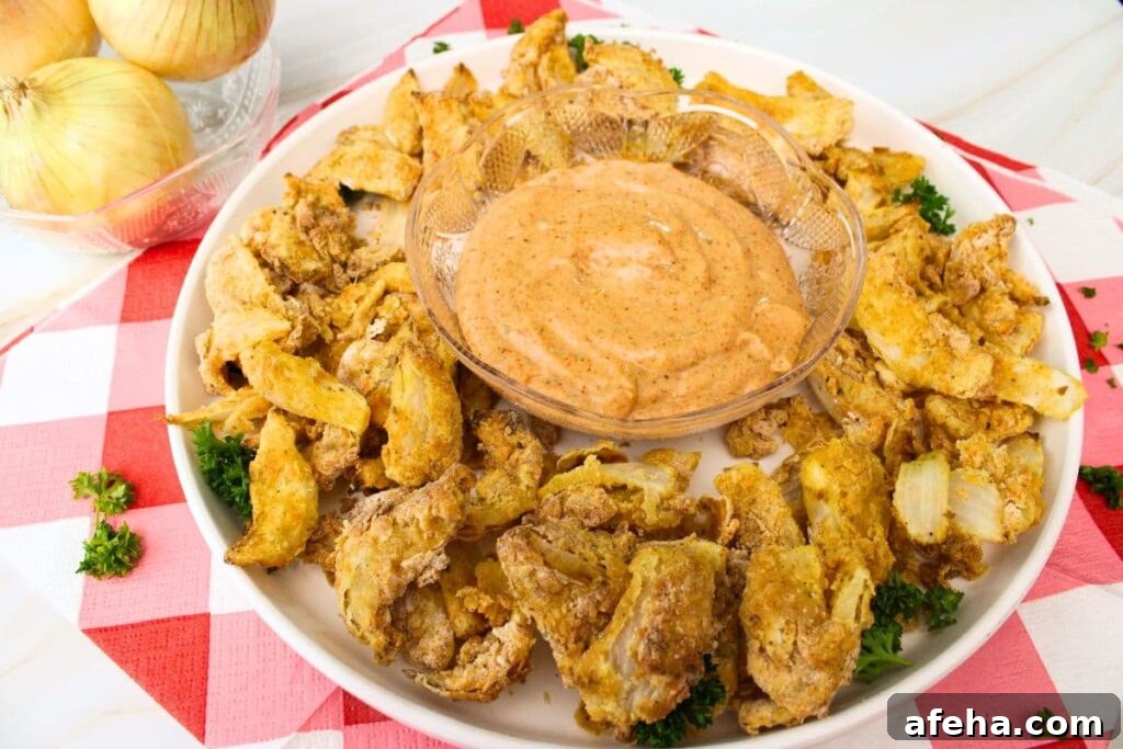 easy air fryer blooming onion petals surrounding a bowl of dip on a plate
