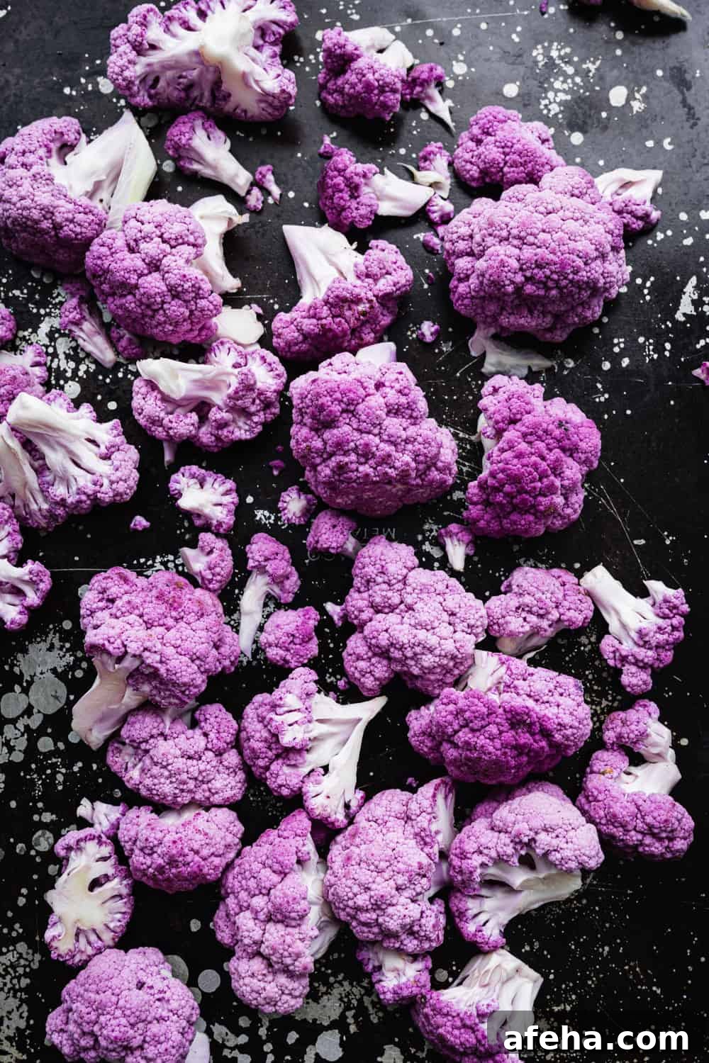 Purple Cauliflower Varieties: Flavor, Nutrition & Cooking Tips 11 purple cauliflower florets on a black baking sheet