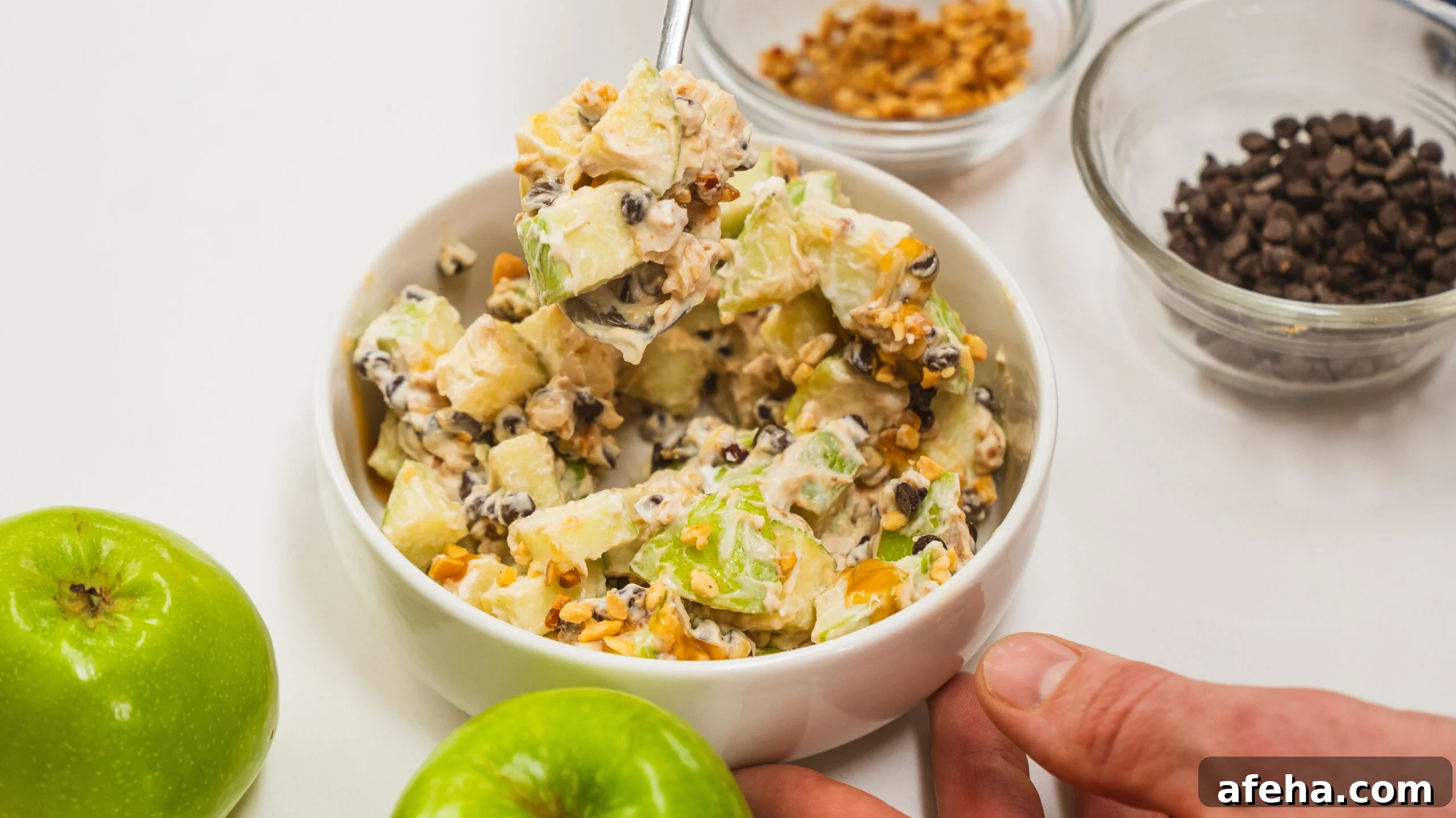 Snicker salad with apples, yogurt, chocolate chips and peanut butter. Green apples are visible to the side.